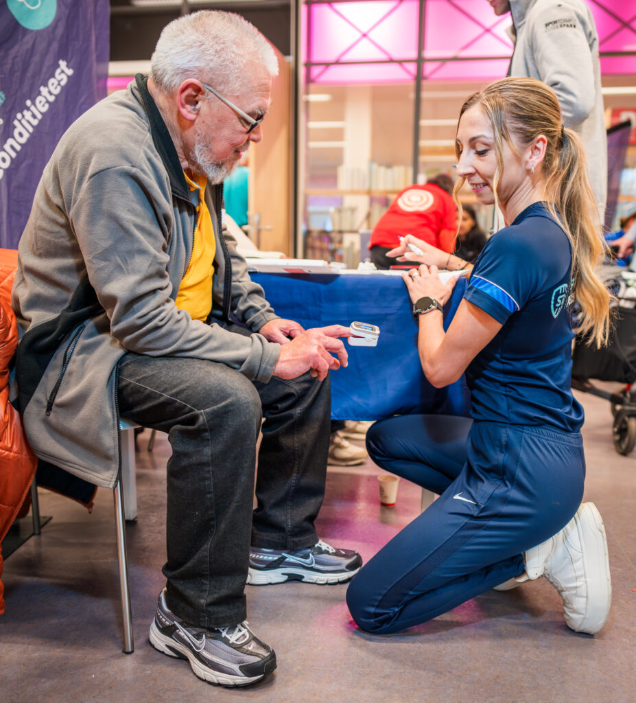 Vitaliteitscoach die een test afneemt bij een oudere meneer